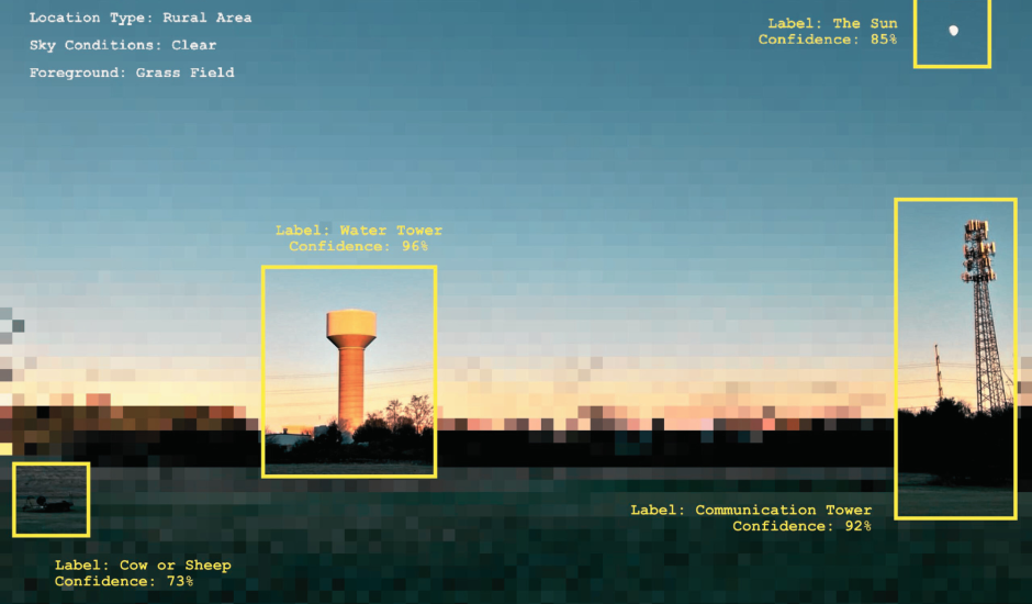 A green field in the foreground, in the back there is a water tower and electricity tower that are squared with a yellow frame. They are identified with AI as buildings. 